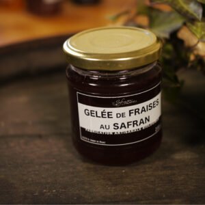 Présentation d'un pot de gelée de fraises au safran, sur le dessus d'un tonneau où un branche de lierre termine le décor