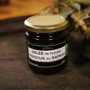 Présentation d'un pot de gelée de fleurs d'Hibiscus au safran, sur le dessus d'un tonneau où un branche de lierre termine le décor