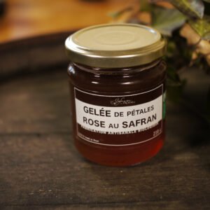 Présentation d'un pot de gelée de pétales de rose au safran, sur le dessus d'un tonneau où un branche de lierre termine le décor