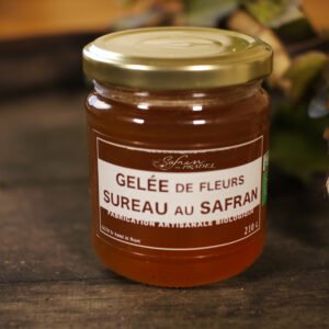 Présentation d'un pot de gelée de fleurs de Sureau au safran, sur le dessus d'un tonneau où un branche de lierre termine le décor