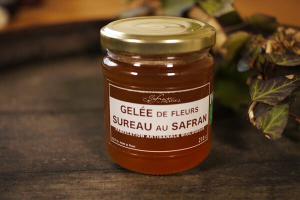 Présentation d'un pot de gelée de fleurs de Sureau au safran, sur le dessus d'un tonneau où un branche de lierre termine le décor